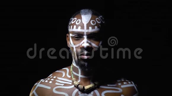 一个肌肉发达的黑人男子在他的身体白色图案描绘了一只老虎在黑暗缓慢的运动视频的预览图