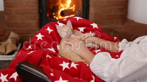 小猫睡在壁炉前的女人圈里视频的预览图