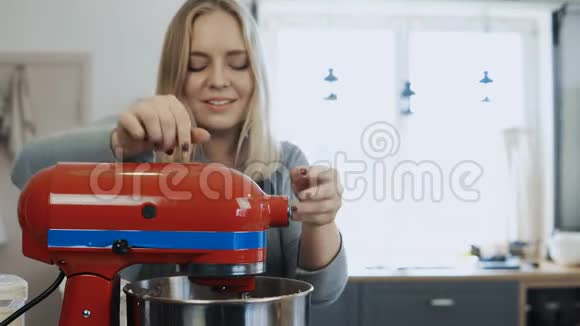 年轻漂亮的女人混合配料用搅拌机对付这个漂亮的女性在厨房做饭视频的预览图