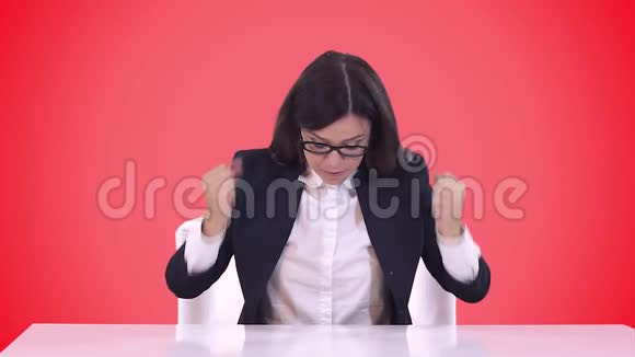 女商人西装革履她坐在一张桌子后面对奴隶挥舞着手臂大喊大叫红色视频的预览图