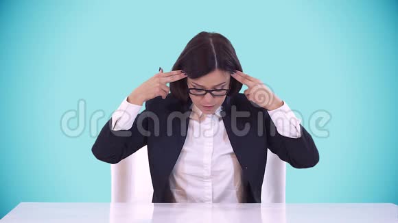漂亮的深色头发戴着眼镜坐在办公桌上穿着商务喊叫蓝色背景视频的预览图