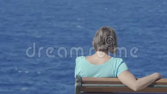 孤独的女人坐在长凳上望着大海视频的预览图