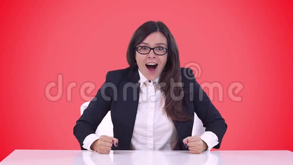 商务女性穿着商务套装坐在办公桌后面享受着一笔不错的交易红色背景视频的预览图