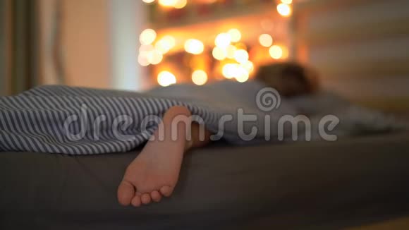 一个睡在床上的小男孩的慢镜头伴随着圣诞灯的灯光照亮了他的一个日历视频的预览图