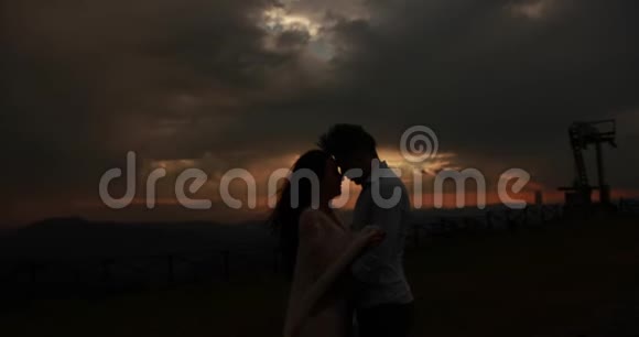 随风而逝一对可爱的情侣站在山上拥抱彼此温柔亲吻的画面视频的预览图