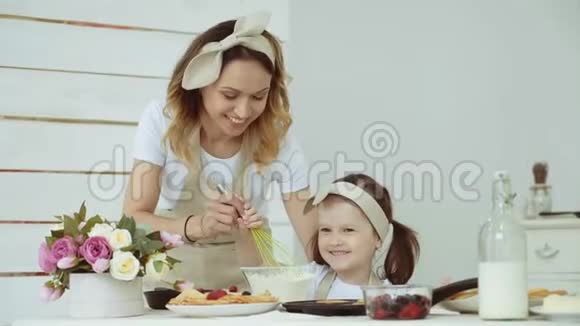 一个小女孩和她的母亲用搅拌器搅拌面粉妈妈教女儿揉面团视频的预览图