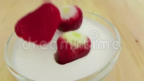 健康草莓在木桌上缓慢下降到白色酸奶中健康食品的概念视频的预览图