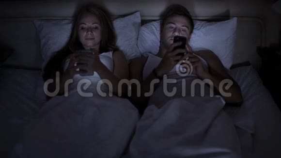 酒店科技互动和幸福的概念带智能手机的微笑情侣在床上视频的预览图