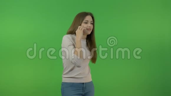 一个留着长发的白人女孩在智能手机上说话在绿色的屏幕上视频的预览图