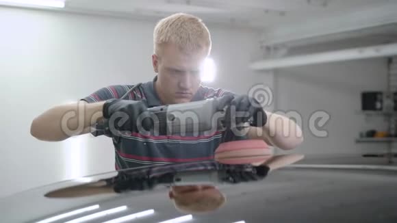 在车库里照顾汽车时使用抛光装置的人视频的预览图