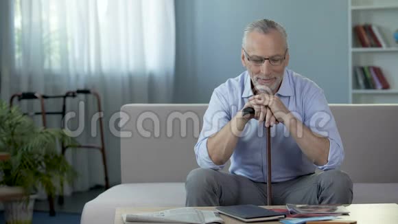 积极的老年男性坐在沙发上思考康复康复视频的预览图