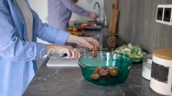 女人正在把西红柿和黄瓜切在白色塑料切割板上然后把它放进沙拉碗里视频的预览图