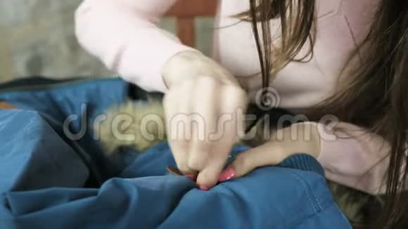 一个女人的特写她用手把一个皮革镶件缝在一件蓝色夹克上视频的预览图