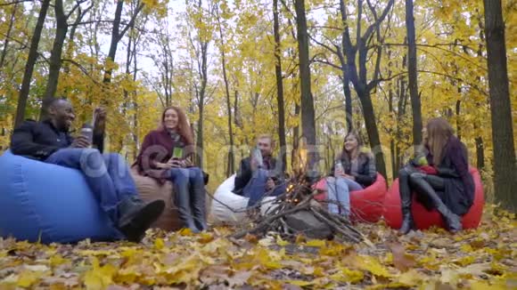 一群朋友坐在炉火前泡着泡芙笑着喝着热水瓶慢动作视频的预览图