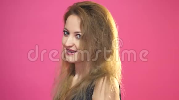 一位微笑的年轻女子在粉红色背景下看着摄像机的肖像视频的预览图