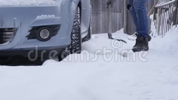 冬天降雪后他在停车场清理汽车周围的积雪手持铁锹的人视频的预览图
