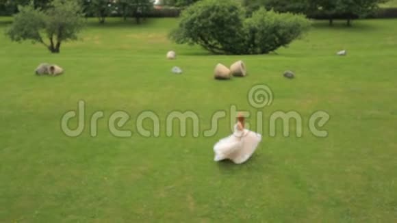 幸福的新娘在绿草上跳舞背景是高山和果园视频的预览图