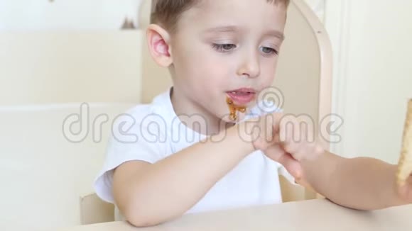 这孩子坐在桌旁在华夫饼锥里愉快地吃着巧克力冰淇淋锥孩子很快乐视频的预览图