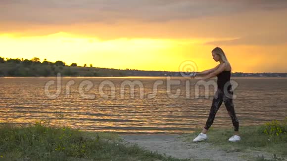 神奇日出时穿着紧身衣的年轻女子在海面上的海滩上练习瑜伽视频的预览图