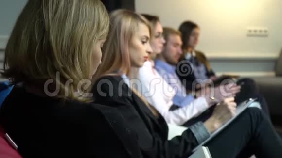 员工在演讲中坐在头巾上写在笔记本上重新调整拍摄的重点视频的预览图