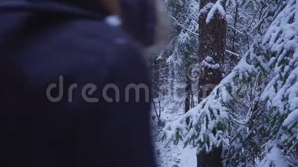 男子走雪冬季森林旅行者与背包看着雪林视频的预览图