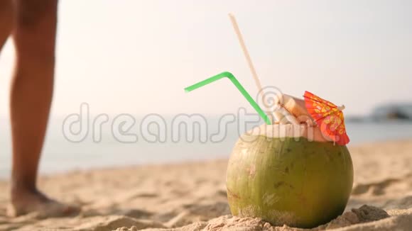 女人在热带海滩游泳后从沙滩上拿起美味的新鲜泰国椰子鸡尾然后走开4K视频的预览图