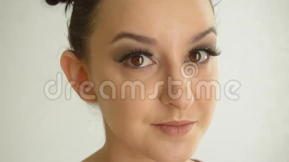 长着假睫毛和棕色眼睛的女性脸看着相机化妆帅气的美少女模特视频的预览图
