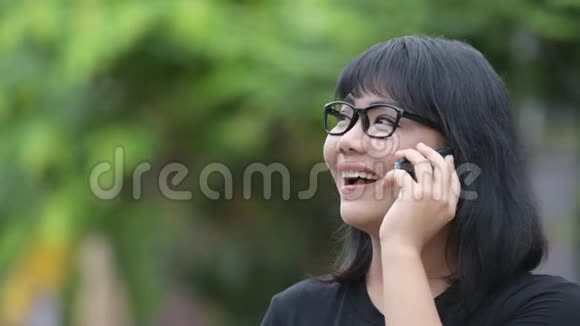 美丽快乐的亚洲女商人在户外街头打电话视频的预览图