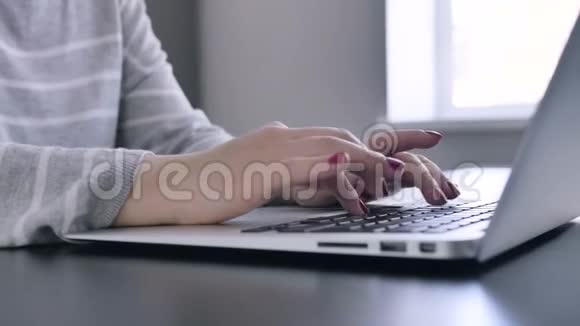 穿着红色指甲的女孩坐在厨房的桌子旁的笔记本电脑里打字视频的预览图