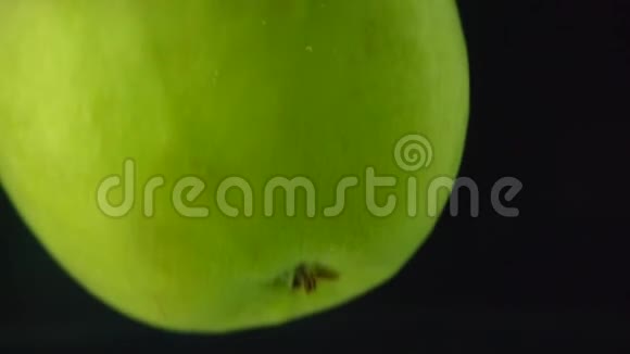 绿色的苹果在黑色背景下缓慢地落入水中视频的预览图