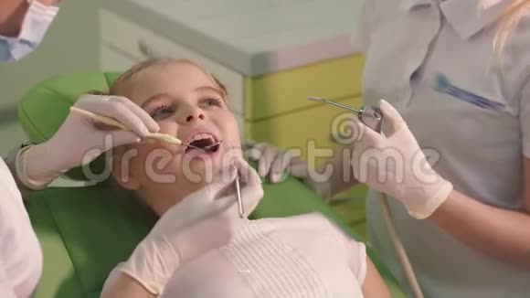 美丽开朗的女孩对待儿童牙医的牙齿她绿色地坐在牙科椅上微笑着视频的预览图