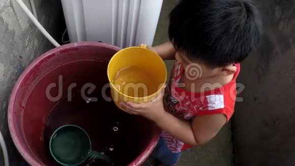 小男孩从塑料桶里舀水视频的预览图