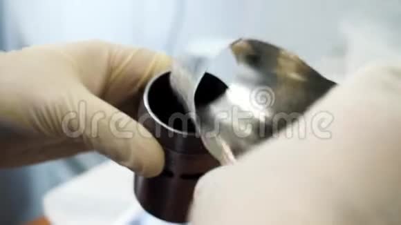 在实验室用医用手套把化学粉末从化学舀到小金属容器里视频的预览图