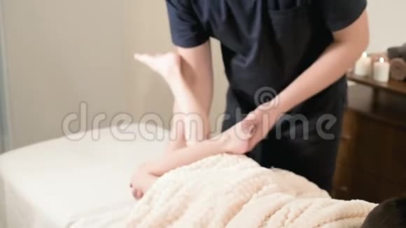 一位男性理疗师按摩师为躺在按摩床上的一个小男孩做了一次轻松的按摩和伸展视频的预览图