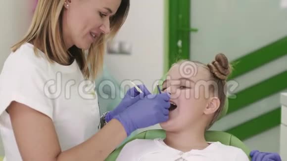 家人和孩子都是牙医看着一个小漂亮女孩嘴里的牙齿视频的预览图
