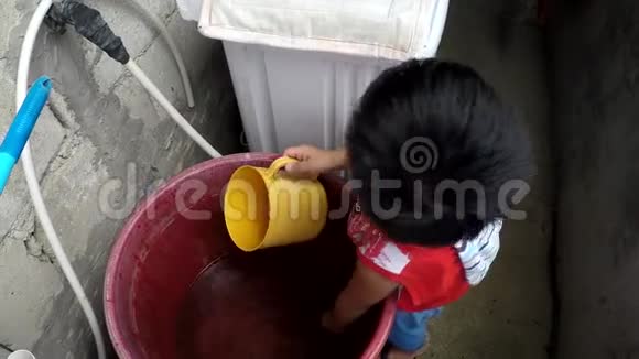 小男孩从塑料桶里舀水视频的预览图