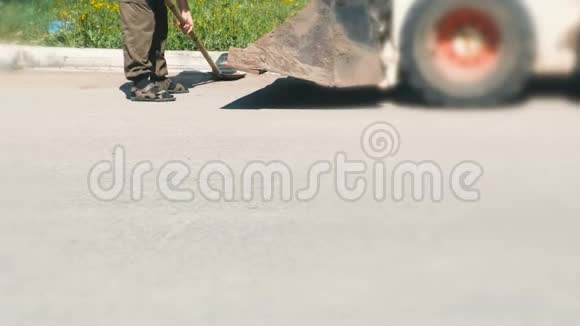 清理城区人用铲子收集泥土把所有东西扔进挖掘机的水桶里腿视频的预览图