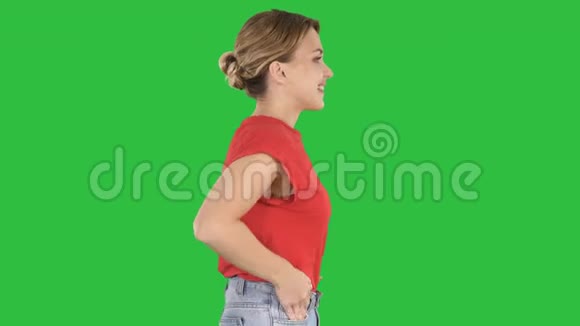 年轻漂亮的女孩双手插在口袋里走在绿色屏幕上Chroma键视频的预览图