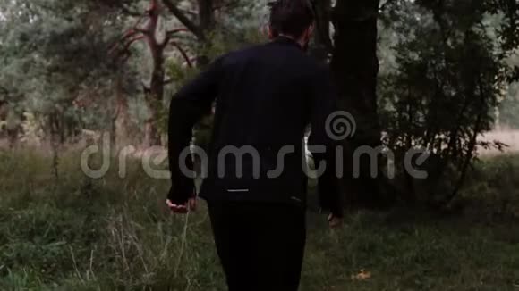 慢动作一个正在探索森林深处的人镜头跟随越野跑者欣赏宁静的秋天风景视频的预览图