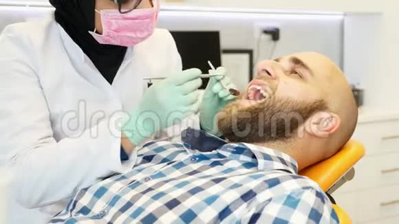 一位研究病人牙齿的穆斯林女牙医看着镜头微笑着视频的预览图