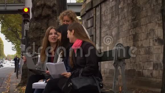欧洲学生拿着笔记本电脑和文件学习慢动作地坐在外面的长凳上视频的预览图