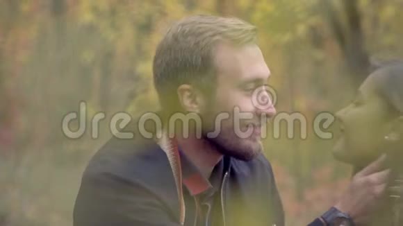 一个长胡子的男人拥抱一个女人在她耳边低语在一个秋天的公园里射击动作很慢视频的预览图