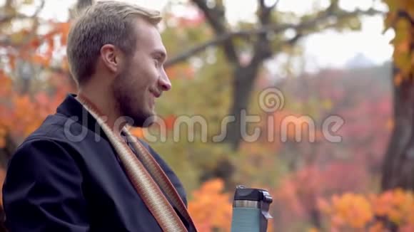 一个快乐的光发男人靠在大自然上用热水瓶喝酒视频的预览图
