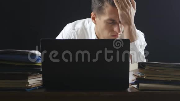 厌倦和压力很大的商人深夜在笔记本电脑上工作视频的预览图