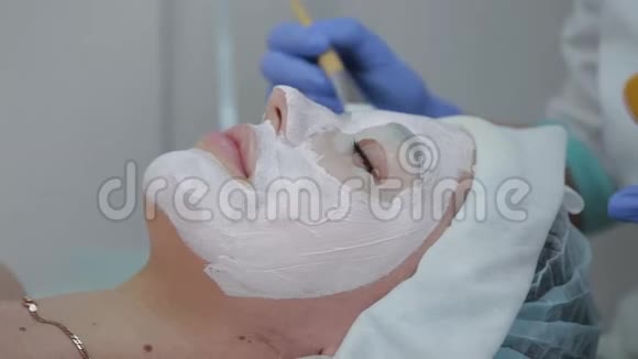 专业美容师女士用脸刷向客户敷面膜视频的预览图