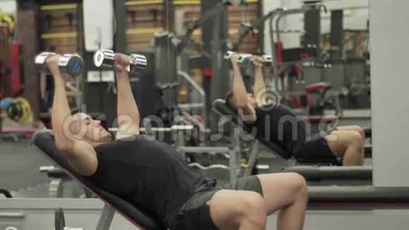 肌肉发达的年轻人在现代健身房用哑铃训练视频的预览图