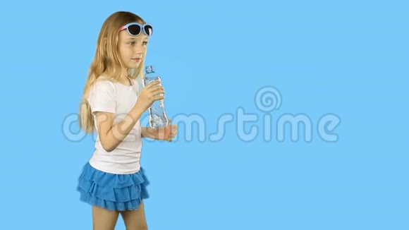 穿着白色t恤的年轻女孩从瓶子里喝着清澈的水竖起大拇指快乐的女孩喝着新鲜的水视频的预览图