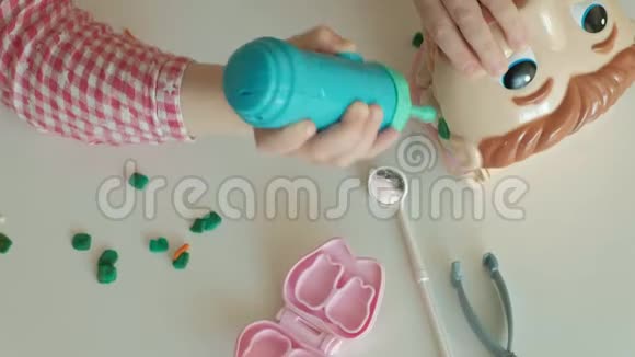 一个女孩用塑料制成牙齿把牙齿插入玩具下巴取下牙套玩视频的预览图