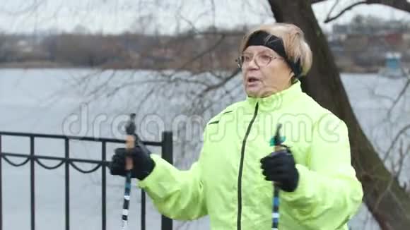 穿绿色夹克的老年妇女在户外做热身运动视频的预览图