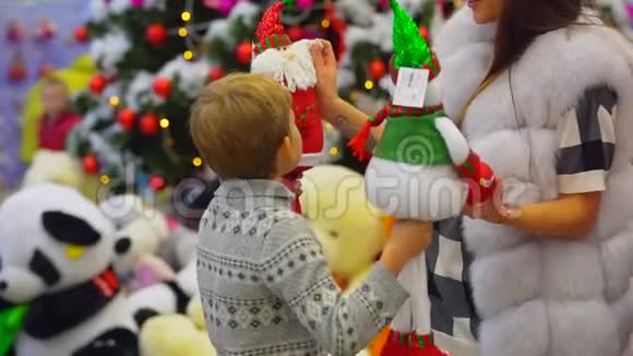 圣诞节假期在商场里的快乐家庭肖像母亲和儿子正在选择圣诞老人的玩具视频的预览图